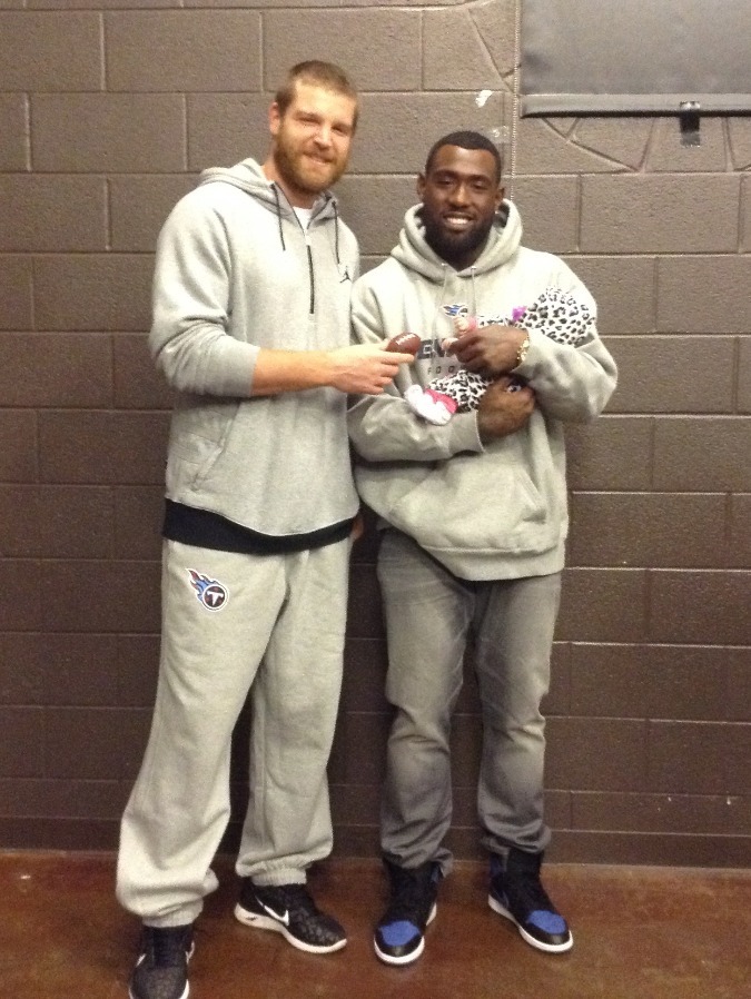 Walker and another Titan's player pose with a baby