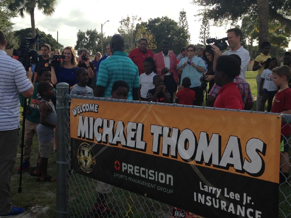 Michael Thomas speaking to the media surrounded by community members in For Pierce, Florida